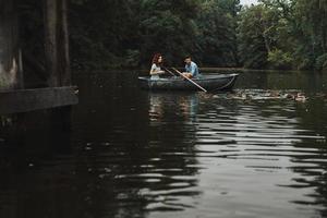 amor verdadero. hermosa pareja joven sonriendo y alimentando patos mientras disfruta de una cita romántica en el lago foto