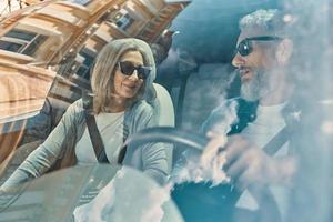 Happy senior couple enjoying car ride while sitting on front seats of the car photo