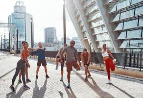 Full length of people in sports clothing warming up and stretching while exercising outdoors photo