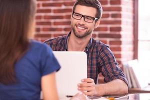 comunicacion de negocios. dos empresarios con ropa informal hablando y sonriendo mientras se sientan cara a cara en la mesa foto