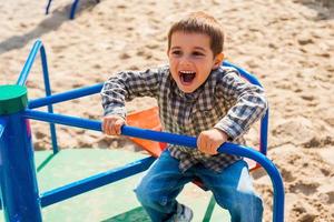 niño juguetón. niño alegre expresando positividad mientras viaja en rotonda foto