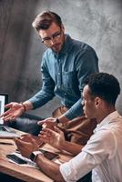 Two young modern men in smart casual discussing something while working in the office photo