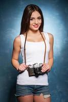 Beauty with camera. Attractive young woman holding camera and gesturing photo