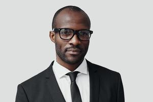 Confident young African man in formalwear looking at camera while standing against grey background photo