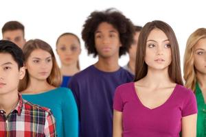 Loneliness in a crowd. Frustrated young woman standing among multi-ethnic group of people and looking away photo