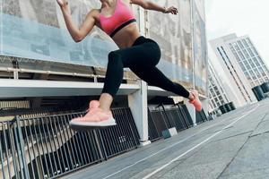 Close-up low angle view of young woman in sportswear running outdoors photo