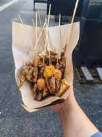 A hand holds a serving of chicken satay which is sold along Jalan Malioboro, Yogyakarta photo