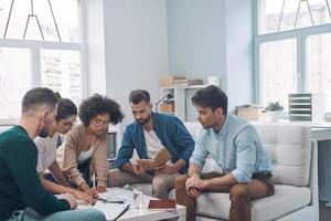 Group of modern young people discussing business while sitting in the office together photo