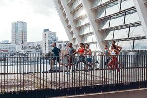 Full length of young people in sports clothing jogging while exercising on the bridge outdoors photo