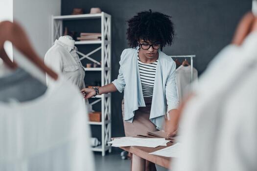 trabajando duro para lograr los mejores resultados. hermosa joven africana midiendo la cintura con cinta y anotando los resultados mientras está de pie en su taller foto