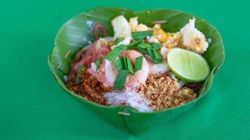 Pad Thai - Birds Eye View, stir fried rice noodle dish in green banana leaves krathong served with lime and spring onion. photo