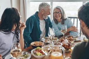 feliz familia multigeneracional comunicándose y sonriendo mientras cenamos juntos foto