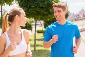 Sport is our life.  Cheerful young woman and man in sports clothing running along the road and smiling photo