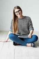 Taking time to relax. Beautiful young woman in striped clothing sitting on the floor and smiling photo