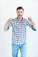 Joy has no limits. Happy young man in shirt gesturing and smiling while standing against white background photo