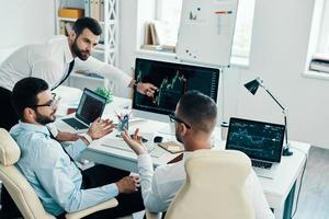 Big data. Group of young modern men in formalwear working using computers while sitting in the office photo