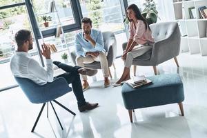 Helping to save marriage. Young married couple talking while sitting on the therapy session with psychologist photo