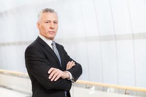 Confident and successful. Confident senior man in full suit holding hands in pockets and looking away photo