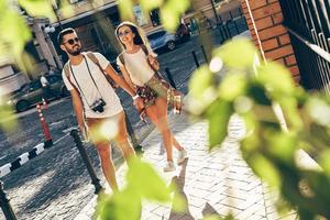 Full length of young couple holding hands and smiling while walking outdoors photo
