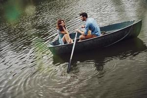 Fantastic way to spend the date. Top view of beautiful young couple enjoying romantic date while rowing a boat photo