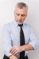 Ready to work. Confident grey hair senior man in formalwear adjusting his sleeve while standing against white background photo