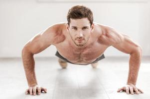 hombre confiado haciendo flexiones. confiado joven musculoso haciendo flexiones y mirando a la cámara foto