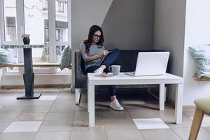 Moments of inspiration. Attractive young woman drawing something in her notebook while sitting on the sofa photo