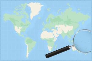 Map of the world with a magnifying glass on a map of Kiribati. vector