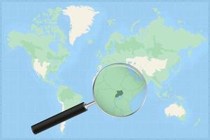 Map of the world with a magnifying glass on a map of Uganda. vector