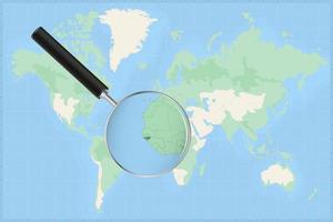 Map of the world with a magnifying glass on a map of Guinea-Bissau. vector