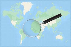 Map of the world with a magnifying glass on a map of Gambia. vector