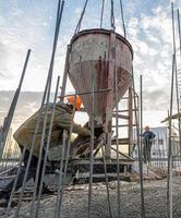 The workers on a building infrastructure roof with machinery and tools. Pouring concrete into a mold photo