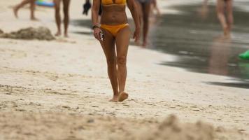 los turistas quemados por el sol disfrutan de unas vacaciones en la playa. mujer caminando en la playa de arena video