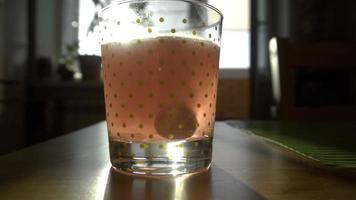 Effervescent tablet in water with bubbles, against influenza, slow motion video