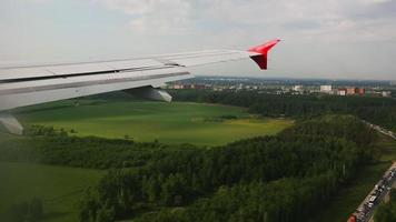 avión de pasajeros acercándose al aterrizaje, punto de vista. vista desde la ventana del avión al bosque verde y la ciudad video