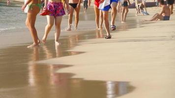 beaucoup de gens marchent le long de la plage de sable par une chaude journée d'été en vacances video