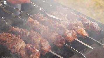 cuisiner des grillades de viande juteuses et savoureuses à l'extérieur. barbecue juteux. l'homme ajoute de la sauce à la viande grillée. fumée de viande lente video