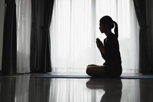 silueta de mujer en posición de oración, manos rezando con fe en la religión y creencia en Dios en un fondo oscuro. poder de la esperanza o el amor y la devoción. gesto de manos namaste o namaskar. foto