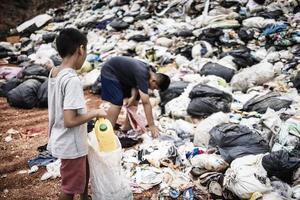 un joven indio pobre recoge botellas de plástico en su saco para ganarse la vida.pobreza, trabajo infantil, trata de personas foto