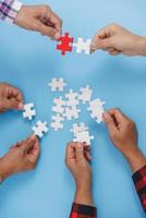 Closeup of businesspeople holding jigsaw puzzle on a blue background. Hand holding the puzzles for the businessmen to work together as a team. Concept of planning work as a teamwork. photo