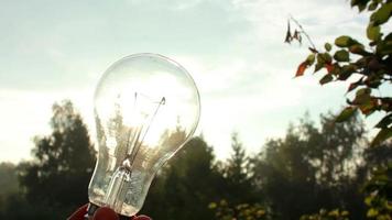 Sun rays are going through the light bulb in a hand. Shallow dof, highly energy concept footage. video