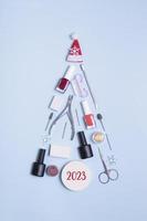 Manicure tools and nail polishes are laid out in the shape of a Christmas tree. 2023 numbers of new year photo