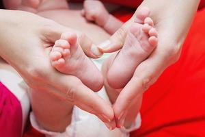 pies de bebé en manos de la madre foto