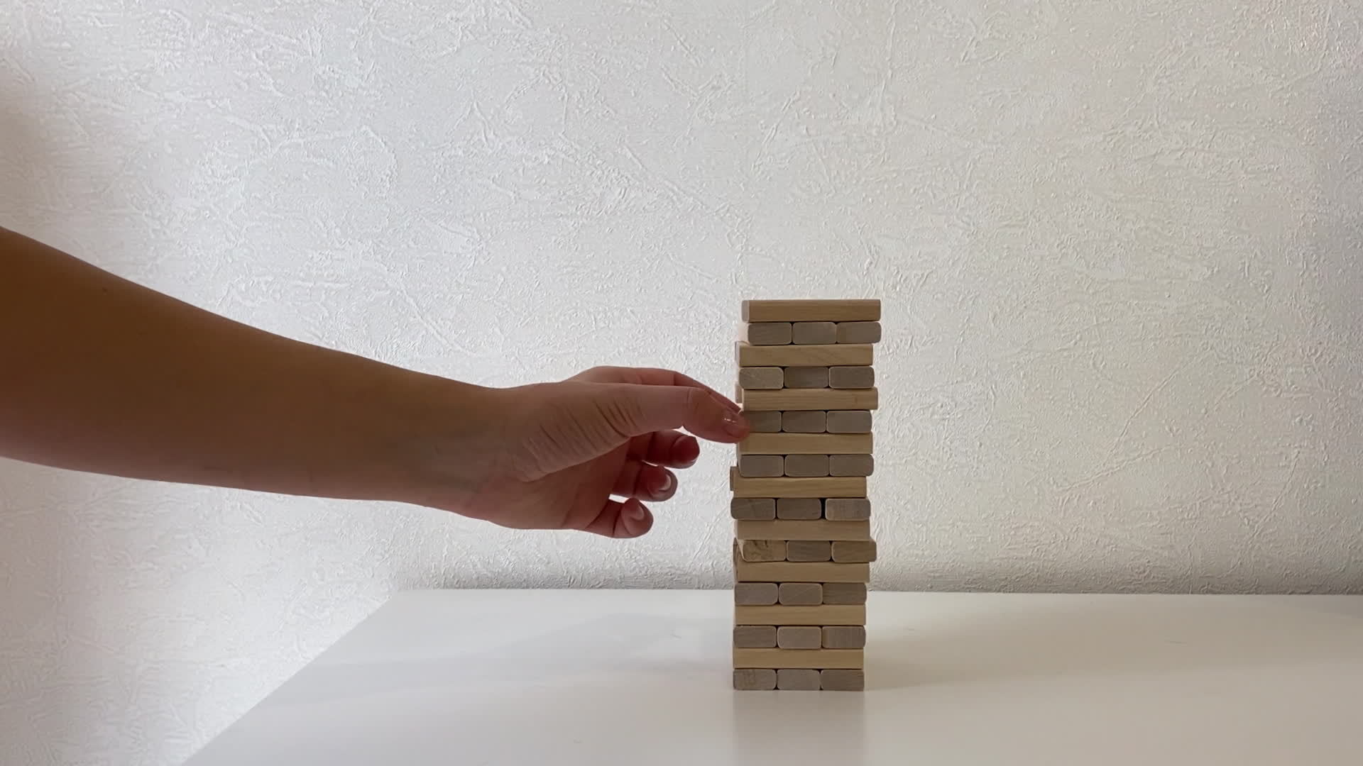 Jenga game. In the video, a woman's hand pushes away wooden jenga dice