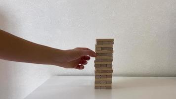 Jenga game. In the video, a woman's hand pushes away wooden jenga dice. video