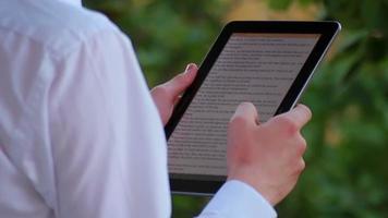 niño adolescente leyendo ipad tablet en el parque video