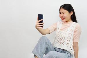 joven mujer asiática alegre sentada y usando un teléfono inteligente. foto