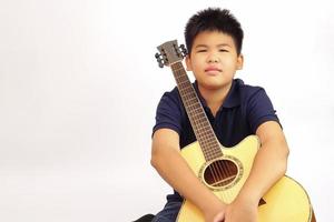 The young boy sit happily hugging his guitar.  Learning and relax concept. photo