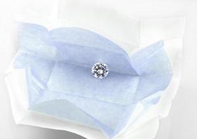 Diamond in open diamond parcel. Round brilliant cut loose diamond in blue parcel paper. photo