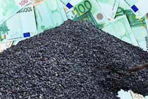 el carbón negro se dobla en forma de montaña y una pala con carbón contra el fondo del papel moneda euro. crisis energética en europa. foto